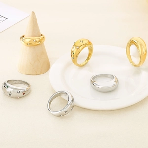 Polished gold and silver rings with zircons on wooden stand and ceramic tray