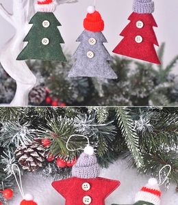 Detail of knitted Christmas star and tree ornaments with wooden buttons on pine branches