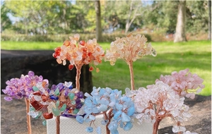 Variety of handmade wire wrapped crystal trees on white bases over a green lawn