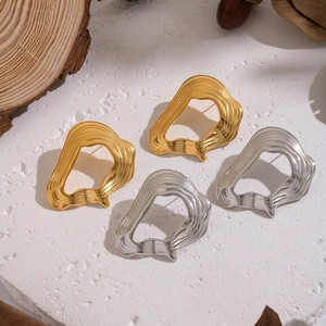 Irregular wavy hoop earrings in gold and silver finish on artistic natural background