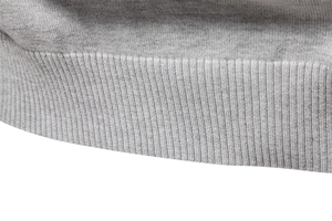 Détail rapproché de la texture du pull en tricot gris avec finitions de bords-côtes