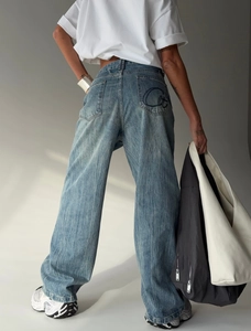 Close-up of vintage washed denim jeans featuring artistic embroidery on the back pocket