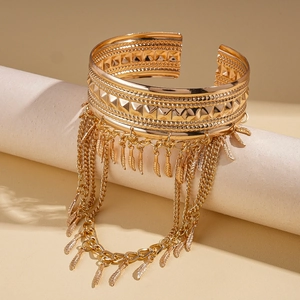 Detail of bohemian gold leaf arm cuff featuring layered tassel chains and feather charms