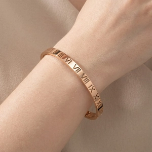 Detailed view of a rose gold titanium bracelet featuring Roman numeral cutout designs