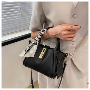 Détail d'un sac seau en cuir noir avec fermoir doré et poignée en foulard pied-de-poule