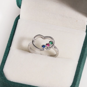 Gros plan détaillé d'une bague coeur en argent avec gemmes colorées en écrin