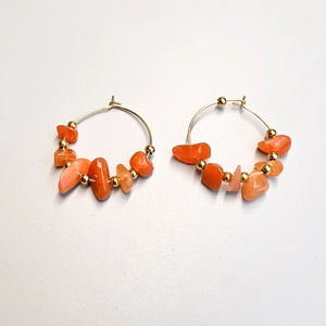 Close-up of bohemian gold hoop earrings with irregular orange stone beads and gold spacers