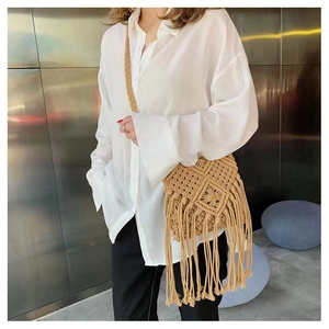 Detail of hand-woven straw crossbody bag with long tassels and beige cotton textures