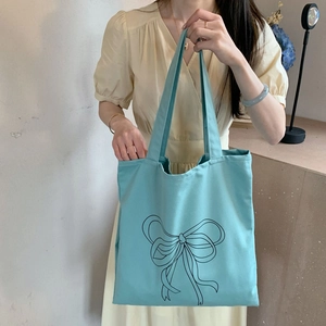 Bolso tote de lona azul con un gran estampado de lazo negro y correas de hombro dobles