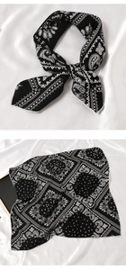 Détail d'un foulard en soie à motif cachemire noir noué en nœud sur soie blanche
