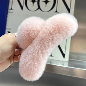 Close-up of fluffy pink faux rabbit fur hair claw clip against a fashion magazine