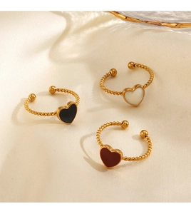 Detailed shot of three gold heart open rings with black white and red enamel on silk