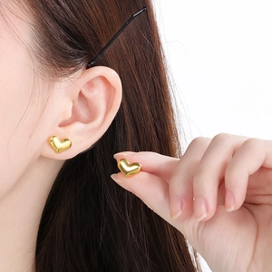 Close-up of heart-shaped 18K gold plated stud earrings on ear for stylish accessory detail