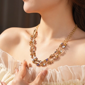 Detail of double-layer gold necklace with colorful crystals on model's neckline