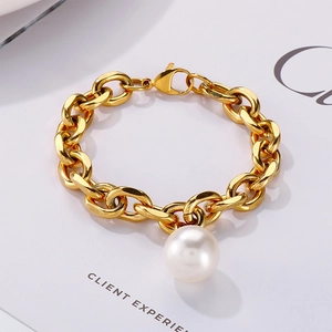 Detail of chunky gold chain bracelet featuring a large white pearl and lobster clasp