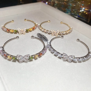 Dettaglio macro di bracciali a farfalla con pietre di zircone in oro e argento