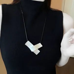 Minimalist irregular geometric pendant necklace with white rectangular accents on black cord