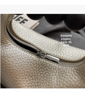 Close-up of smooth silver zipper and pearl handle on champagne textured leather bag