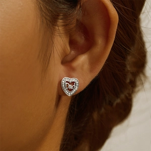 Macro detail of 925 silver heart stud earrings with Dad lettering and sparkling zircons