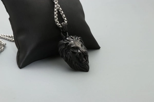 Detailed close-up of a carved black lion head pendant with a silver metal chain link