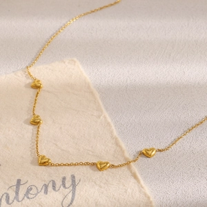 Detail view of 18K gold plated heart necklace with multiple charms on an O-chain