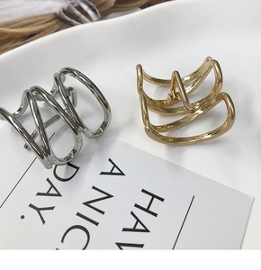 Close-up of gold and silver wavy metal hair clips on a ceramic plate with card