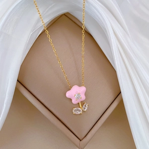 Detailed close-up of a pink enamel flower pendant with zircon accents on gold chain