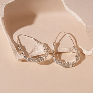 Macro shot of silver liquid metal irregular earrings with flowing lava texture detail