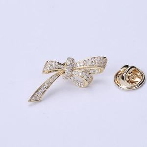 Detailed view of a gold bow brooch with micro-set cubic zirconia and its metal backing