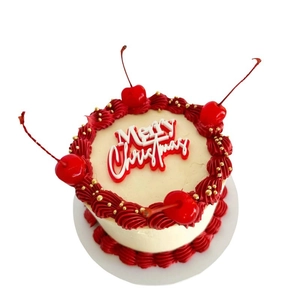 Acrylic Merry Christmas cake topper on white cream cake with red frosting and cherries
