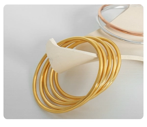Vista dettagliata di bracciali minimalisti opachi in oro, oro rosa e argento su pietra