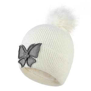 Detail of knit winter hat with fluffy pompom, rhinestone butterfly and fleece lining