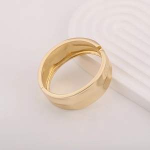 Minimalist wide gold bangle featuring a high-polish finish and unique concave metal texture