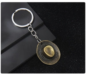 Macro shot of bronze cowboy hat keychain with detailed texture on dark matte background
