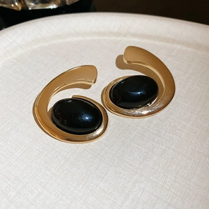 Detailed view of gold oval earrings with black resin inlay on a neutral tray