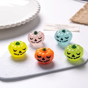 Detailed view of colorful Halloween mini pumpkin resin ornaments in five vibrant colors