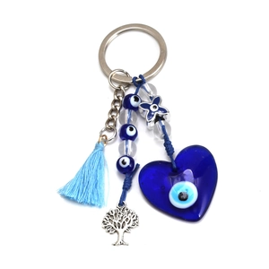 Detail view of heart-shaped evil eye pendant with silk tassel and tree of life charm
