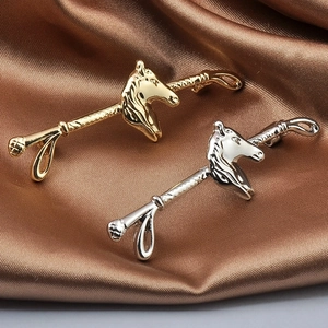 Detailed close-up of gold and silver horse head brooches on elegant brown silk fabric