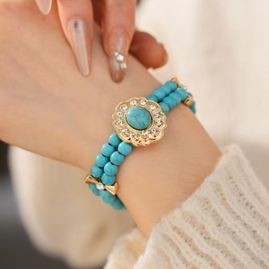 Gros plan d'un bracelet en perles turquoise à double rangée avec fleur en strass