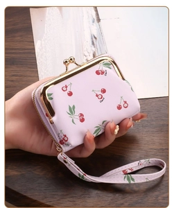 Close-up of pink cherry pattern card holder with golden metal clasp and wrist strap