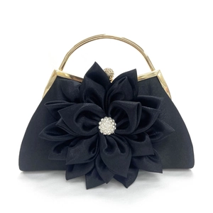 Detalle de bolso de fiesta de satén negro con flor de tela 3D y decoración de cristal fino