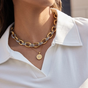Detail of layered sun pendant necklace with mixed gold and silver link chain on a model