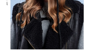 Detail of black faux leather vest with lamb wool collar and metal zipper over grey knit sweater