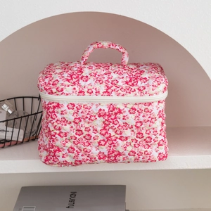 Detail of pink floral quilted makeup bag with soft fabric handle and zipper closure