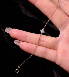 Detail of a delicate 18k gold plated S925 silver anklet with a diamond clover charm.