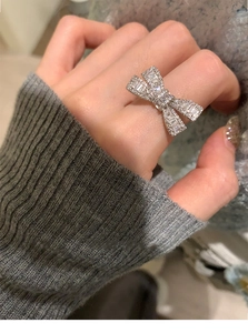 Detailed view of silver bow ring with pave-set cubic zirconia on female hand