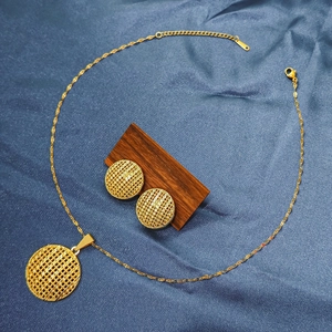 Detailed view of gold mesh pendant necklace and stud earrings set on blue silk
