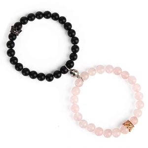 Detail of magnetic couple bracelets with matte onyx beads and golden crown charms