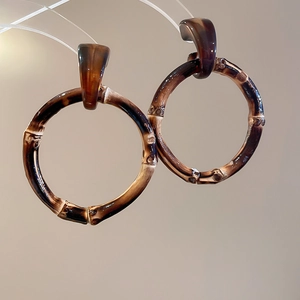 Detail view of tortoiseshell brown resin hoop earrings with a natural bamboo-like texture