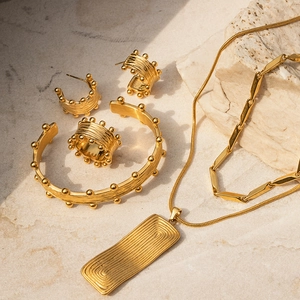 Detail shot of 18K gold plated stainless steel jewelry set with wood grain texture finish